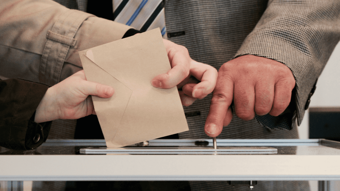 Personas depositando su voto en una urna transparente