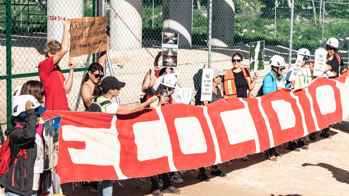 Fotografía de activistas con una manta que dice Ecocidio