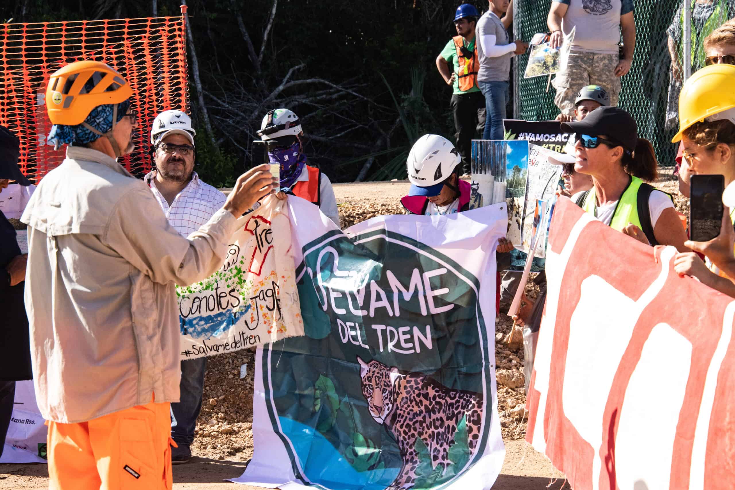 Fotografía de un grupo de personas protestando, se ven varias mantas, una de ellas de Selvame del Tren.
