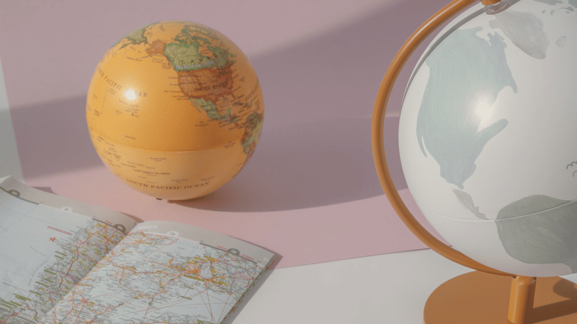 imagen de un mapa de américa latina y dos globos terraqueos sobre un fondo rosa. Fotografía elegida para el artículo Las presidentas en América Latina